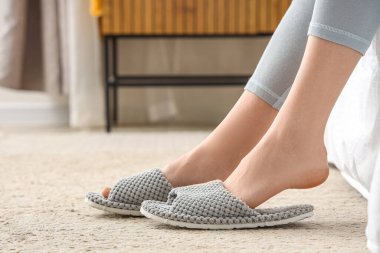 Evde yumuşak terlikli genç bir kadın, yakın plan.