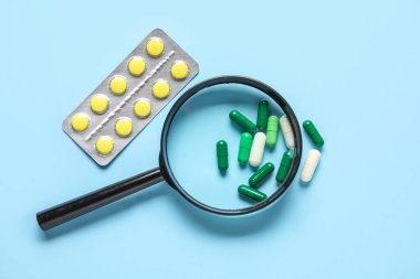 Mavi arka planda farklı haplar içeren büyüteç