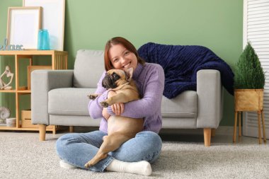 Genç bayan evde sevimli köpeğe sarılıyor.