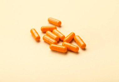 Bej arka planda turuncu tıbbi kapsüller, yakın plan