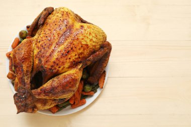 Ahşap zemin üzerinde Şükran Günü için lezzetli kızarmış hindi ve farklı sebzelerle dolu bir tabak.