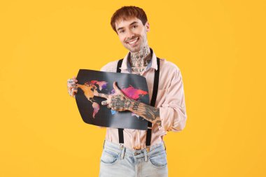 Sarı arka planda dünya haritası olan mutlu genç adam.