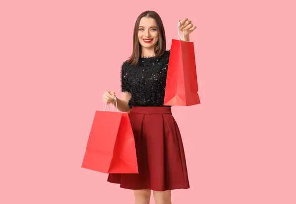 ピンクの背景にショッピングバッグを持っている若い女性 — ストック写真