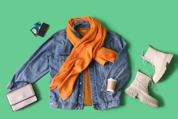 Winter clothes with accessories, mobile phone and credit cards on green background