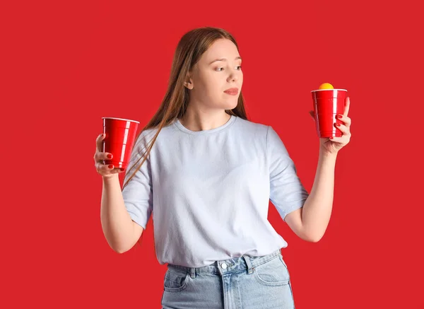 Junge Frau Mit Bier Und Ball Auf Rotem Hintergrund — Stockfoto