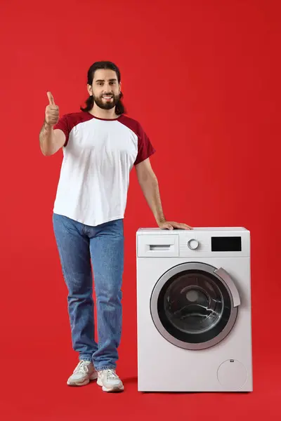 빨간색 배경에 엄지손가락을 보여주는 세탁기 — 스톡 사진