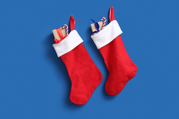 Рождественский носок с подарочными коробками и леденцами на синем фоне