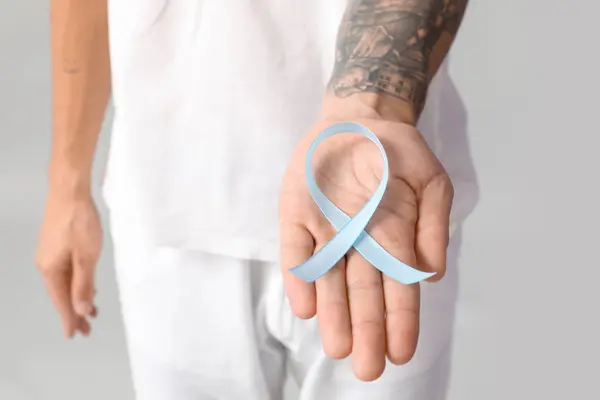 Handsome man with blue ribbon on grey background. Prostate cancer concept