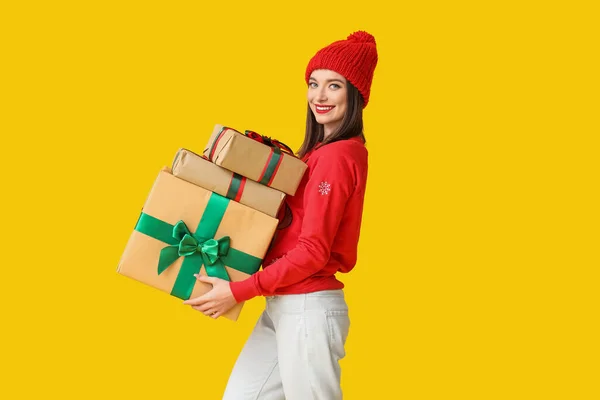 黄色の背景にクリスマスギフトボックスを持っている若い女性 — ストック写真