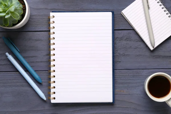 Kalemli defterler ve mavi ahşap arka planda bir fincan lezzetli kahve.