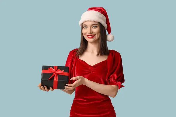 青い背景にクリスマスギフトボックスとサンタの帽子の若い女性 — ストック写真