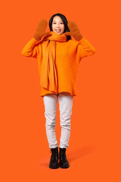 オレンジ色の背景に冬服でアジアの若い女性 — ストック写真