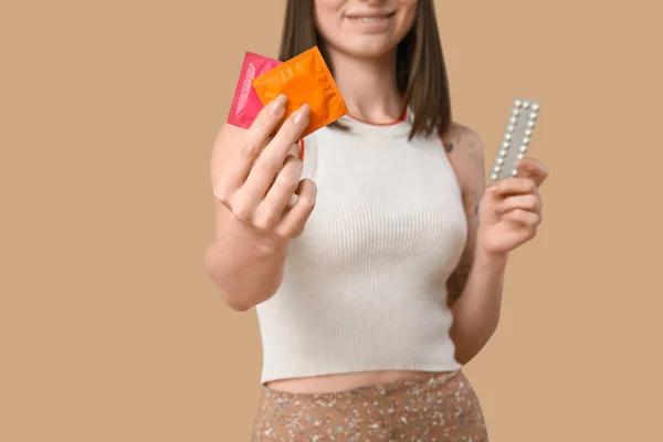 Krásná Mladá Žena Antikoncepčními Pilulkami Kondomy Hnědém Pozadí Koncepce Povědomí — Stock fotografie