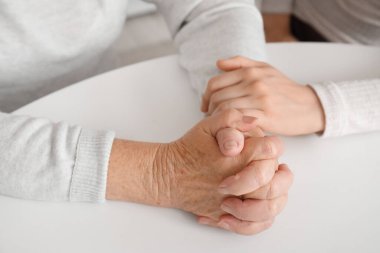 Mutfakta büyükannesiyle el ele tutuşan genç kadın, yakın plan.