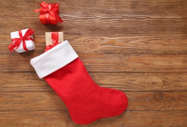 Noel çorabı ve tahta arka planda hediye kutuları.