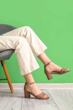 Renkli duvarın yanındaki koltukta oturan şık ayakkabılı kadın.