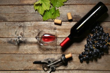 Ahşap arka planda üzümlü bir bardak ve bir şişe nefis şarap.