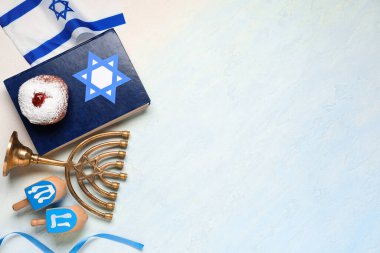 Açık mavi arka planda Tevrat, menorah, donut ve dreidels ile Hanuka kompozisyonu