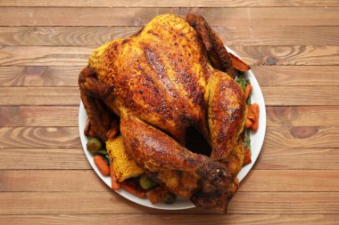 Ahşap zemin üzerinde Şükran Günü için lezzetli kızarmış hindi ve farklı sebzelerle dolu bir tabak.