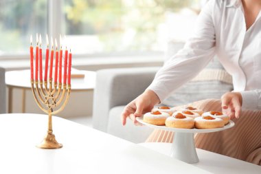 Hanukkah 'ı evde menorayla kutlayan donutlu genç bir kadın, yakın plan.