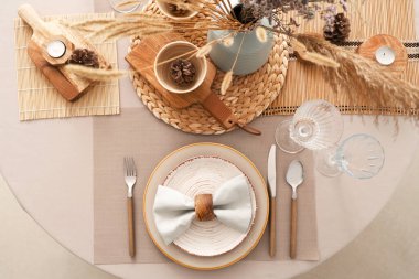 Sofra takımı, tabaklar ve kurumuş çiçeklerle süslenmiş.