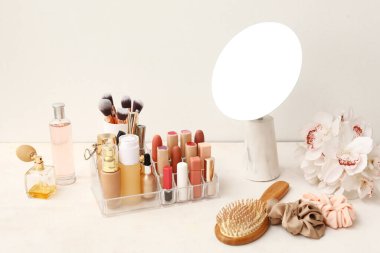 Farklı dekoratif kozmetik ürünleri ve beyaz masadaki ayna.