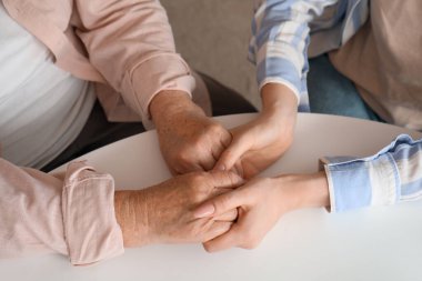 Mutfakta büyükannesiyle el ele tutuşan genç kadın, yakın plan.