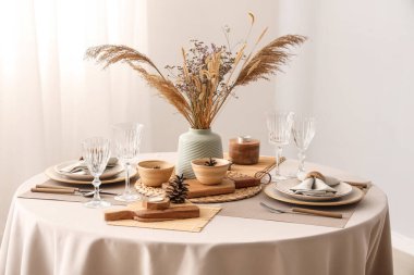 Kurumuş çiçekleri, otları ve çam kozalakları olan zarif bir masa.