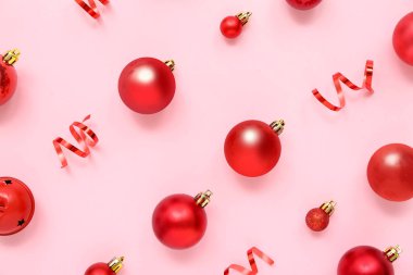 Kırmızı Noel topları ve pembe arka planda kurdeleleri olan kompozisyon