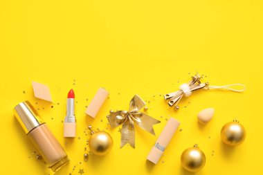 Sarı arka planda güzel altın Noel süslemeleri ve makyaj ürünleri