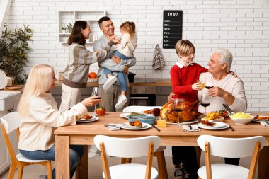 Şükran Günü 'nde mutlu bir aile şenlik masasında yemek yiyor.