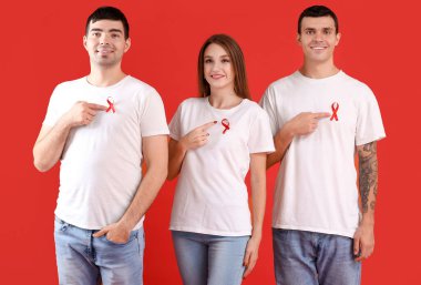Renkli arka planda kırmızı kurdeleli bir grup genç. Dünya AIDS Günü konsepti