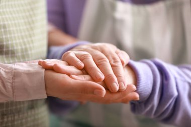 Genç kadın ve büyükannesi mutfakta el ele tutuşuyorlar.