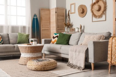 Sörf tahtası, masa ve kanepelerle aydınlık oturma odasının içinde.