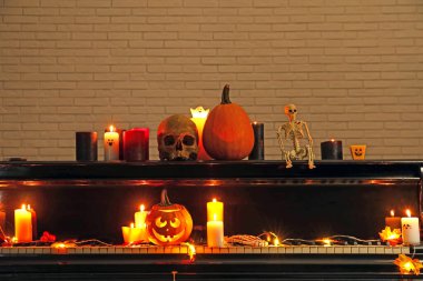 Büyük piyano, yanan mumlar ve karanlık odada Cadılar Bayramı dekoru.