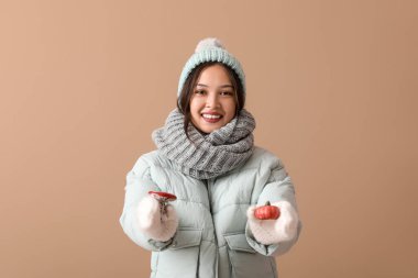 Kahverengi arka planda dekoratif oyuncakları olan sıcak eşarplı güzel Asyalı kadın.