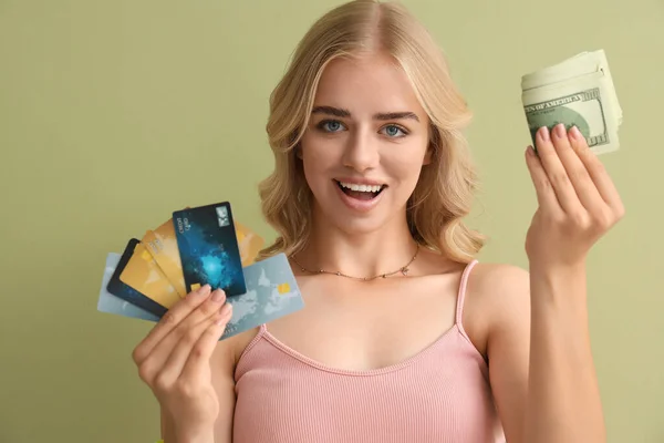 Young woman with credit cards and cash on green background, closeup