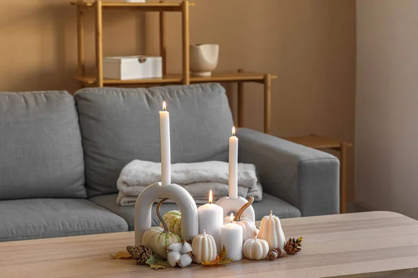 Burning candles and beautiful autumn decor on wooden table in room