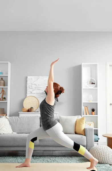 stock image Beautiful young woman in sportswear practicing yoga at home