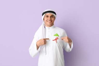 Yakışıklı Müslüman adam mor arka planda kırmızı kurdele ve prezervatif gösteriyor. AID farkındalık kavramı