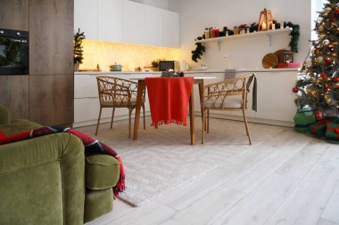 Mutfağın içinde tezgahlar, yemek masası ve Noel ağacı var.