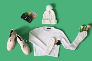 Aksesuarlı kışlık kıyafetler, ödeme terminali ve yeşil arka planda kredi kartları