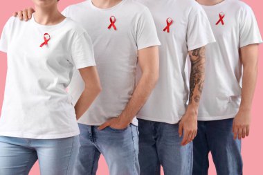 Pembe arka planda kırmızı kurdeleli bir grup insan. Dünya AIDS Günü konsepti