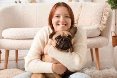 Genç bayan evde sevimli köpeğe sarılıyor.