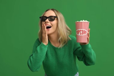 Yeşil arka planda patlamış mısır kovası olan 3 boyutlu gözlüklü genç bir kadın.