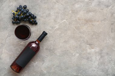 Gri arka planda üzümlü bir bardak ve bir şişe nefis şarap.
