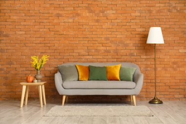 Oturma odasının içinde gri kanepe, yastıklar ve kahve masasında balkabakları.