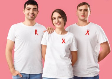 Pembe arka planda kırmızı kurdeleli bir grup genç. Dünya AIDS Günü konsepti