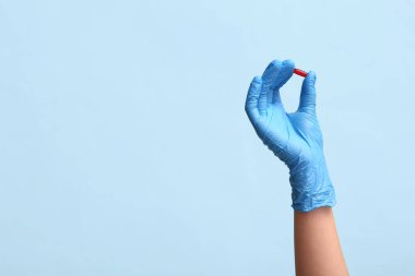 Mavi arka planda hapları olan eldivenli bir doktor.