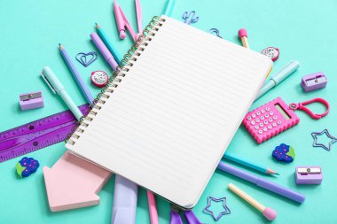 Mavi arkaplanda farklı kırtasiye malzemesi olan defter